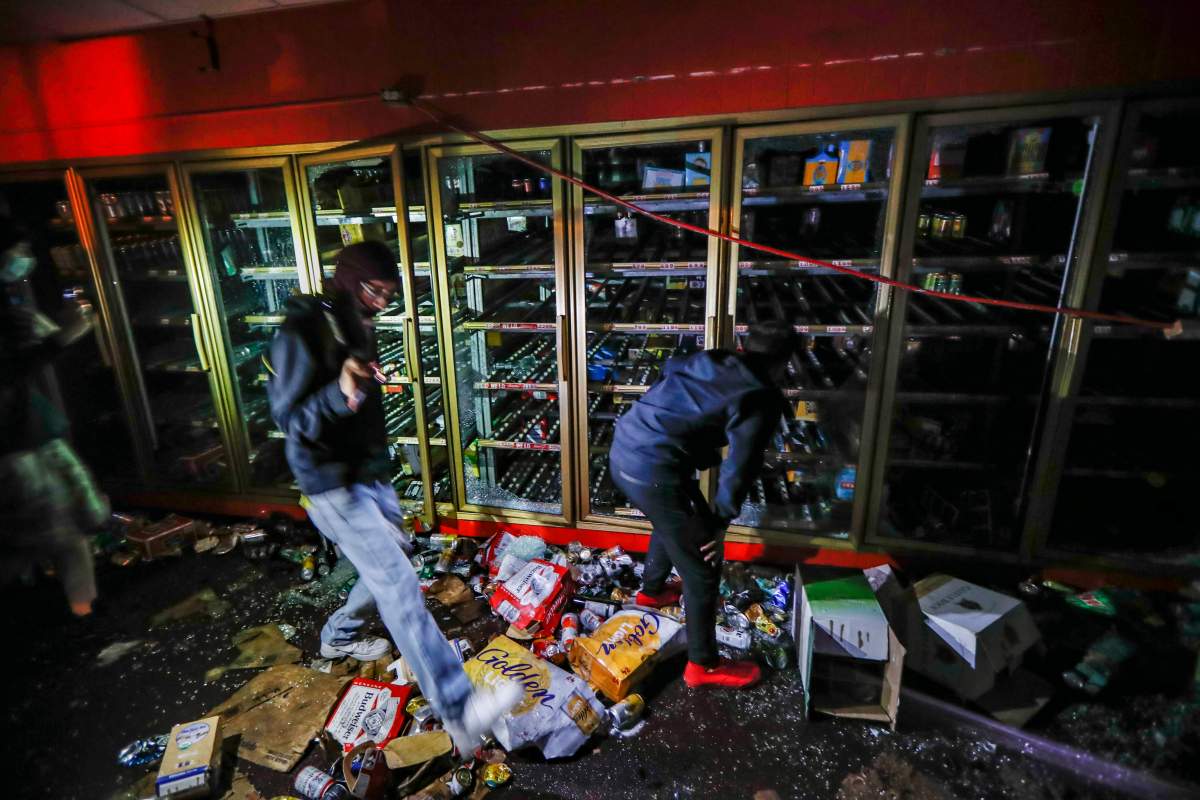 Protestors search within a burning liquor store near the Minneapolis 3rd Police Precinct, Thursday, May 28, 2020, in Minneapolis. (AP Photo/John Minchillo)