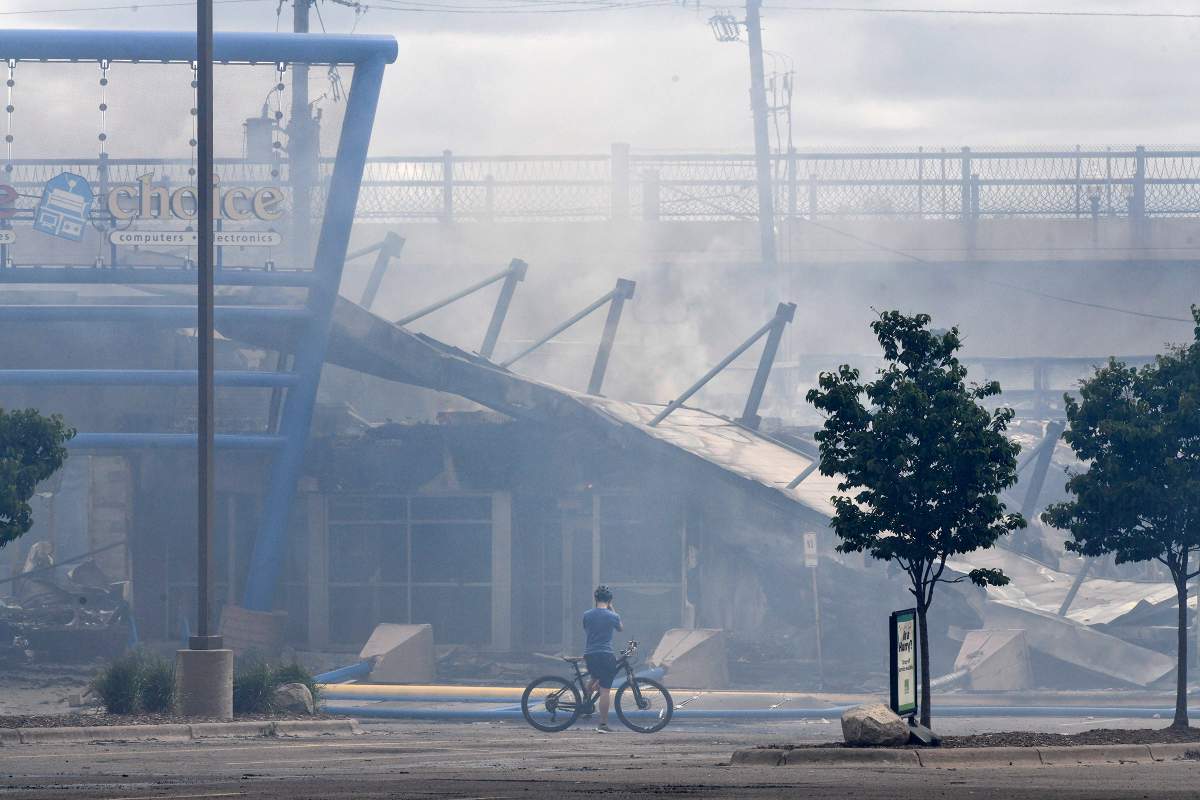 Smoke rises from a strip mall near the intersection of Lake Street and Hiawatha Avenue Friday, May 29, 2020, in Minneapolis, Minn Protests over the death of George Floyd in Minneapolis police custody have spread to other areas across the United States. (Dave Schwarz/The St. Cloud Times via AP)
