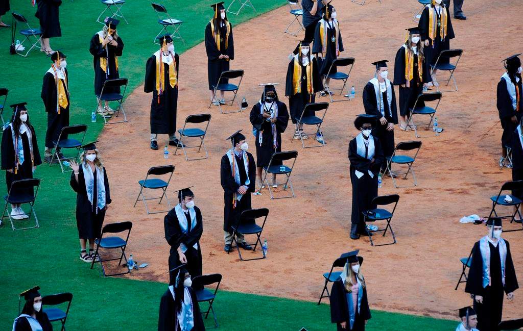 Seniors from Spain Park High School stand on a baseball field at a socially distanced graduation ceremony in Hoover, Ala., Wednesday, May 20, 2020. Health officials say usual graduation ceremonies could endanger the public health by promoting the spread of disease. But school officials say they're using social distancing guidelines and abiding by state health rules. (AP Photo/Jay Reeves).