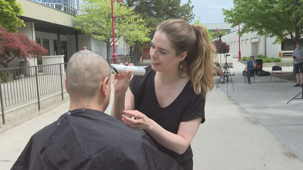 Westbank First Nation Chief Christopher Derickson’s wife helps to shave his head for a fundraiser on Sunday.