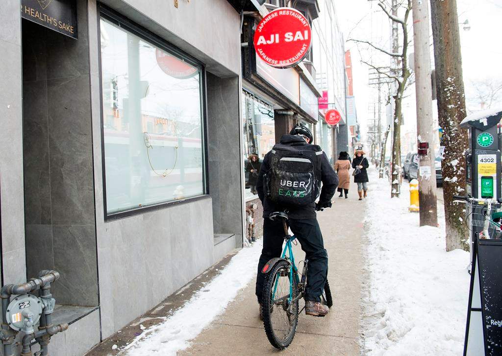 An Uber Eats courier is pictured as they pick up an order for delivery from a restaurant in Toronto, Thursday, Feb. 27, 2020.