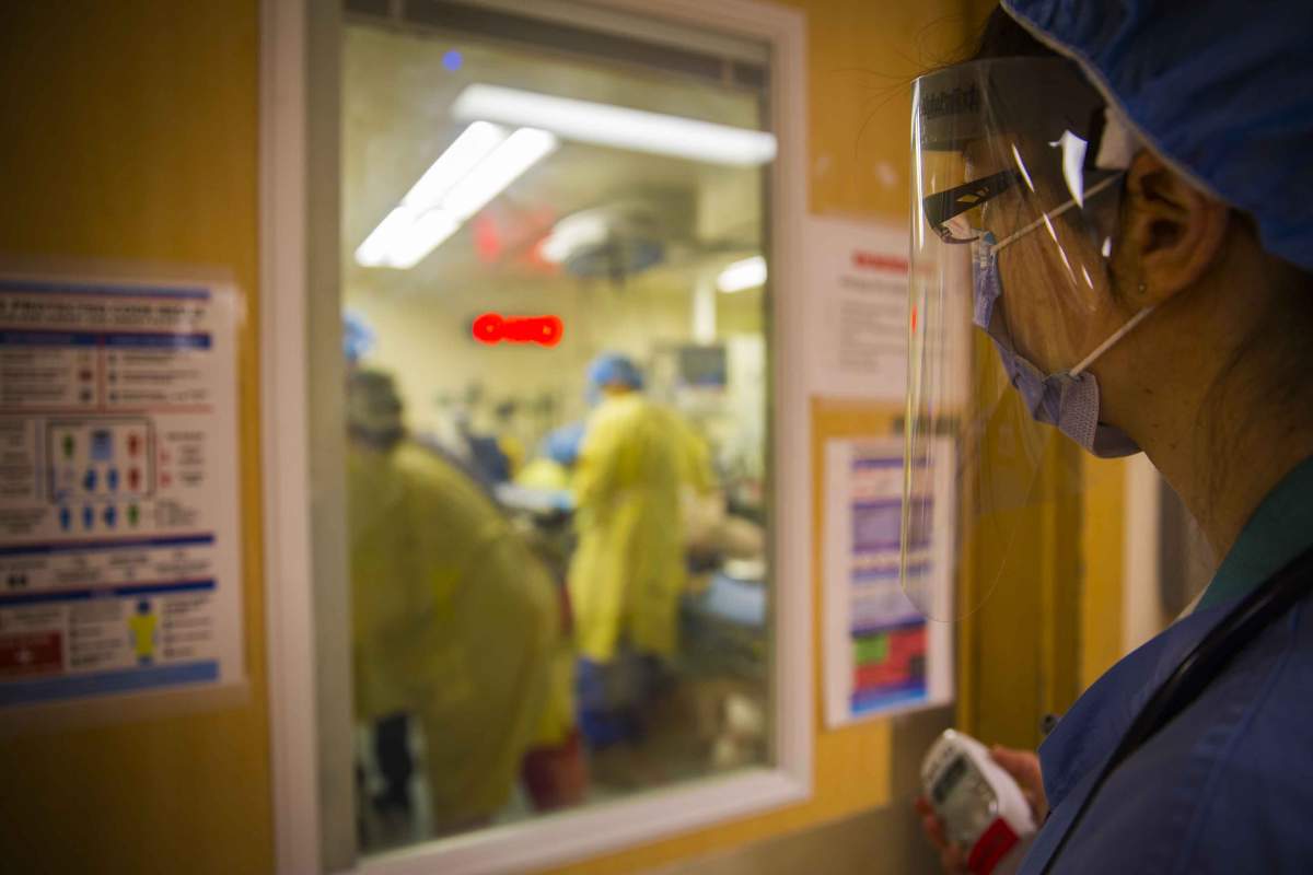 This emergency physician, acting as the “runner doctor,” clutches a baby monitor to communicate with the Emergency Medicine Team of nurses, doctors, and respiratory therapists at the patient’s bedside. They are conducting a Protected Code Blue, which signifies the patient’s unknown COVID-19 status and that it’s an emergency intubation – inserting a breathing tube.