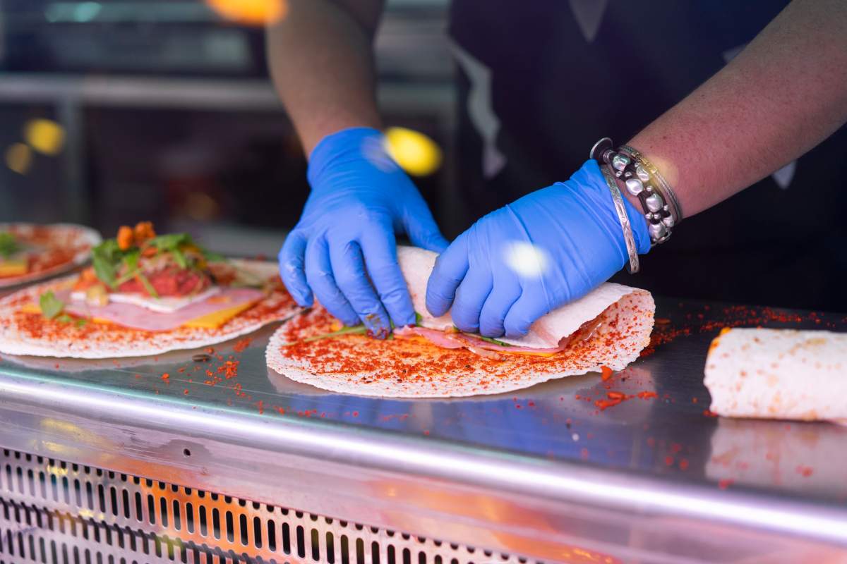 A stock image of a worker making a tortilla wrap.