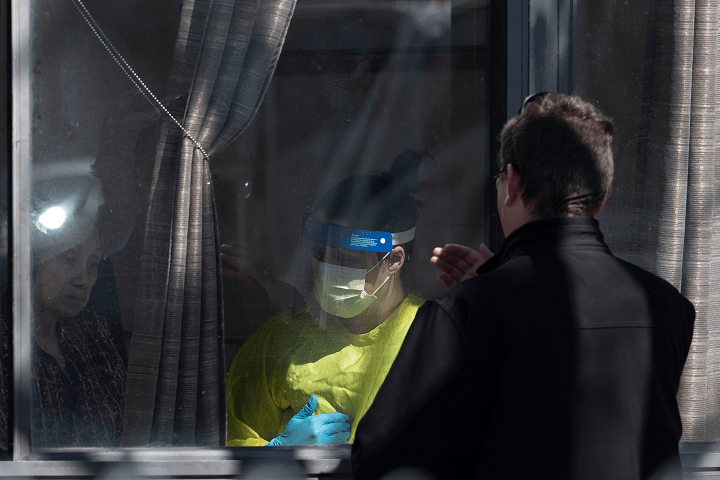 Father David Sherry crosses himself as he offers a blessing and absolution to a COVID-19 positive resident, identified as Flora, at Orchard Villa Care home, in Pickering, Ont. on Saturday, April 25, 2020.