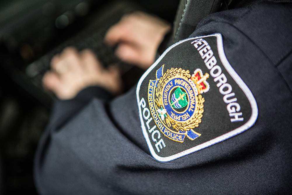 A Peterborough Police Service officer types away on a computer inside a police cruiser.