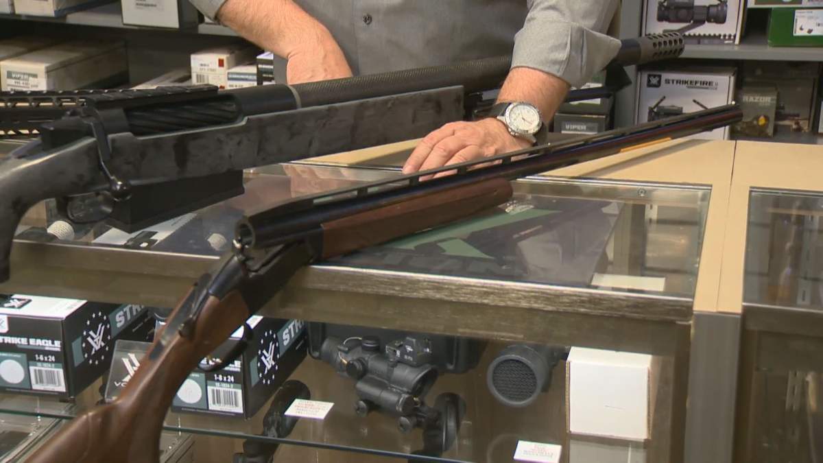 A Calgary gun store owner shows off some of the rifles that are now illegal in Canada in a May 28, 2020 photo.