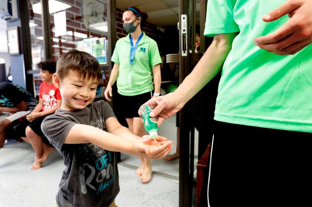 Bruce McCall, 5, smiles as he takes hand sanitizer during martial arts daycare summer camp at Legendary Blackbelt Academy in Richardson, Texas, Tuesday, May 19, 2020.