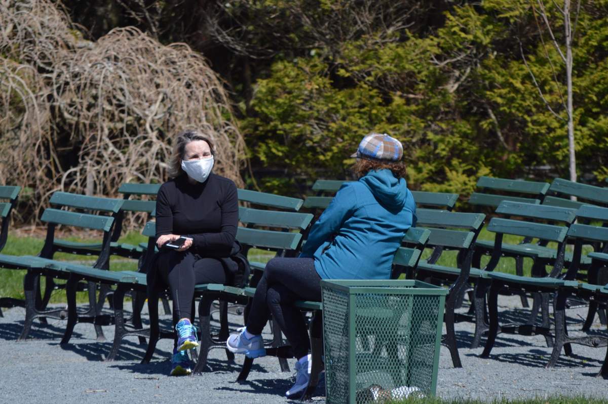File - Two women, one of whom is wearing a mask, speak in the Halifax Public Gardens.