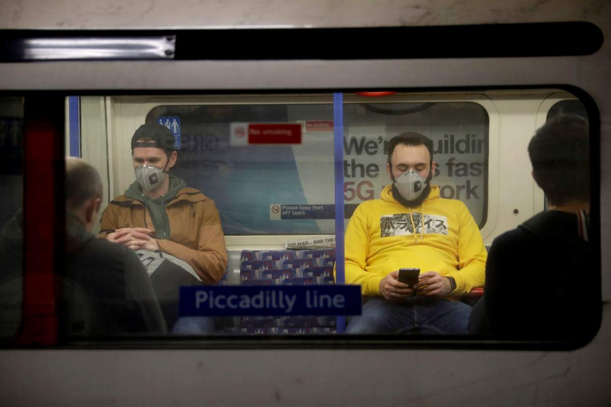 FILE - In this Friday, March 20, 2020 file photo, passengers wearing face masks travel on a Piccadilly Line underground train in London.