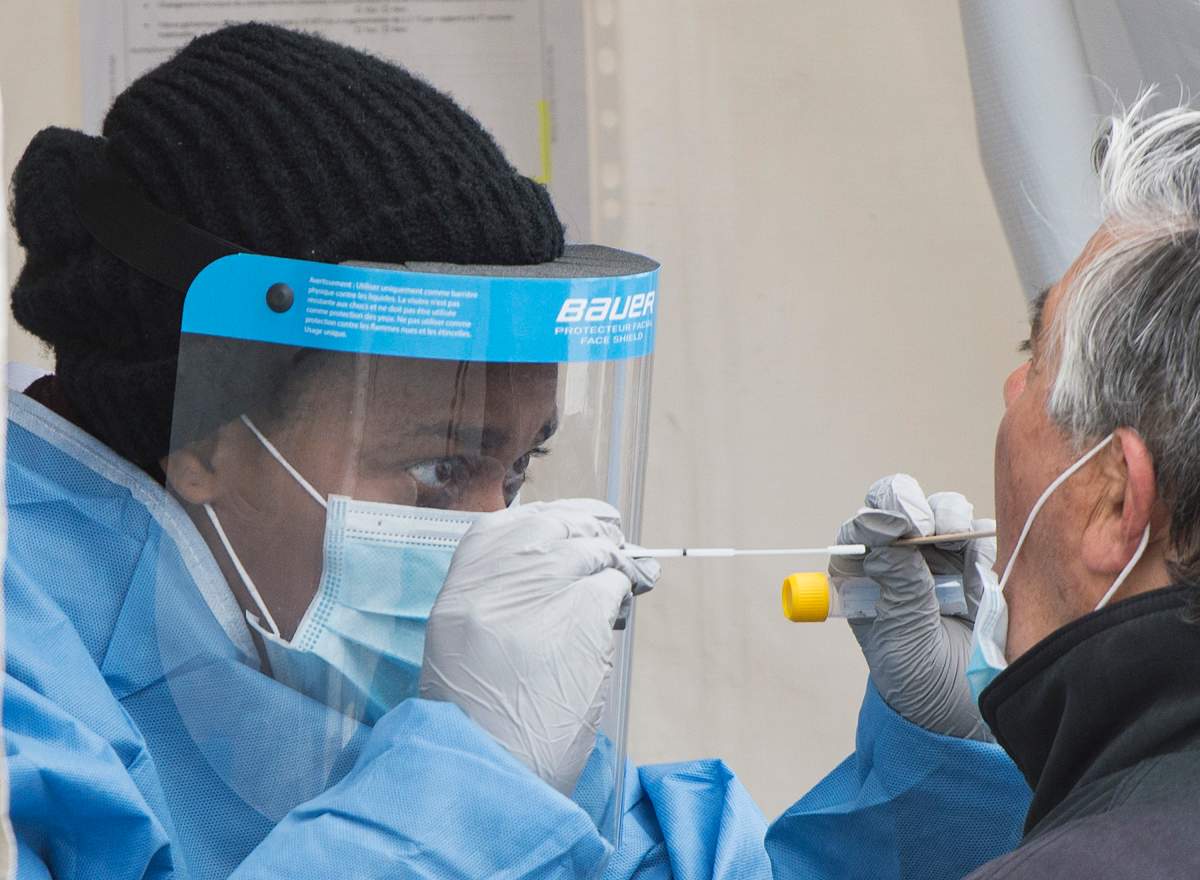 A health-care worker prepares to swab a man at a walk-in COVID-19 test clinic in Montreal North, Sunday, May 10, 2020.