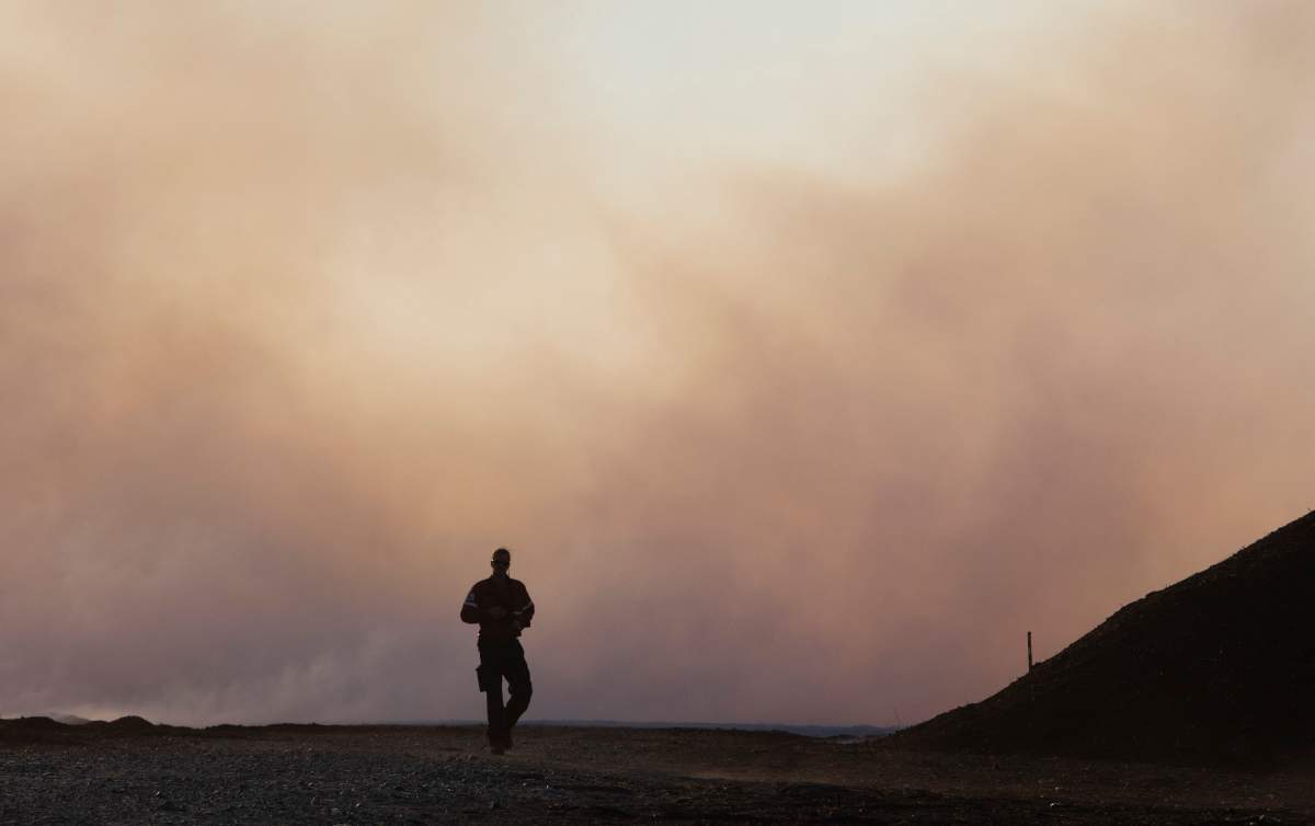 A firefighter walks toward a major field and forest fire at Lambert Peat moss fields in Riviere-Ouelle, Que., Friday, June 19, 2020. The fire spread over more than 10 km, pushed by strong winds.