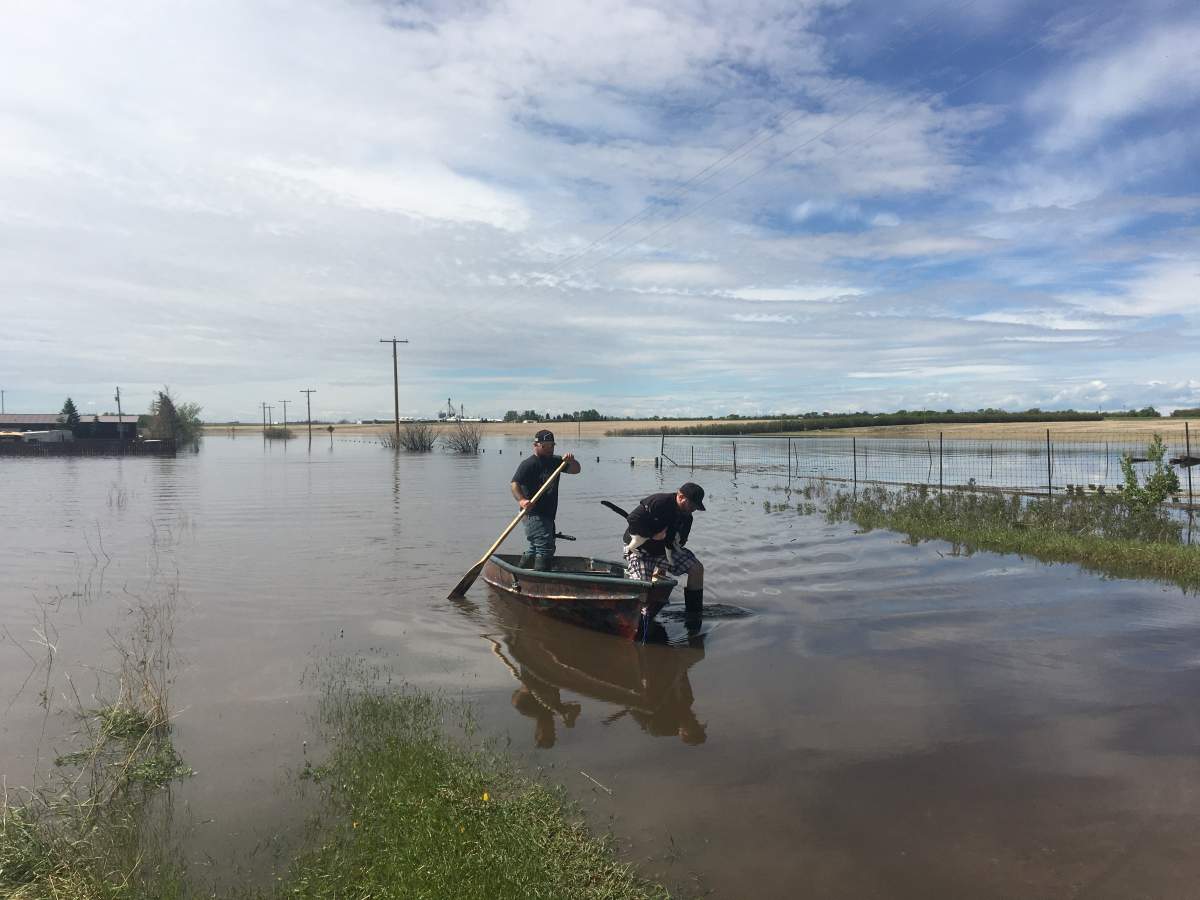 Residents use a boat to get across flooded areas in Acme, Alta. on Monday, June 1.