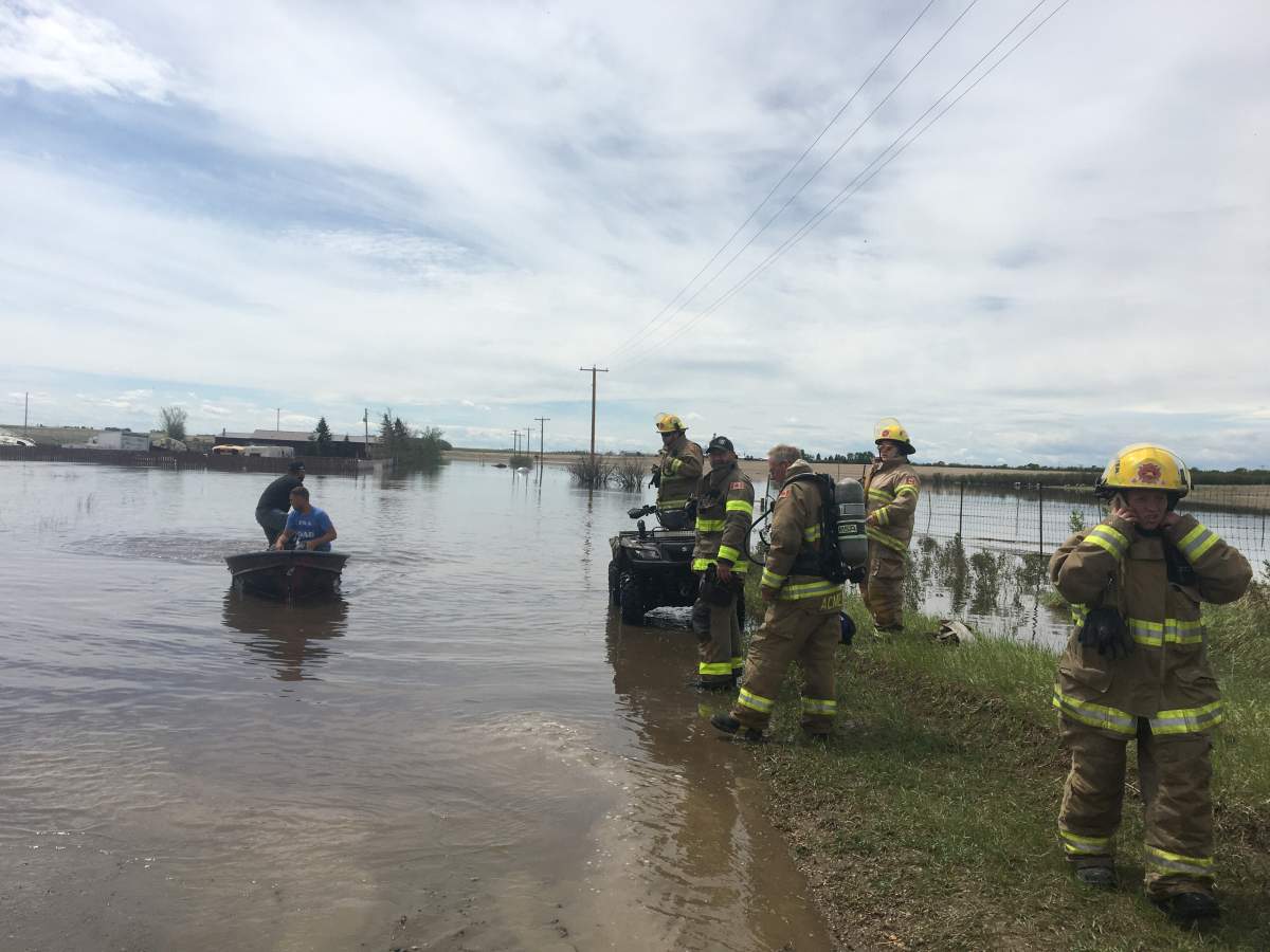 Firefighters are seen in a flooded area of Acme, Alta., on Monday, June 1.