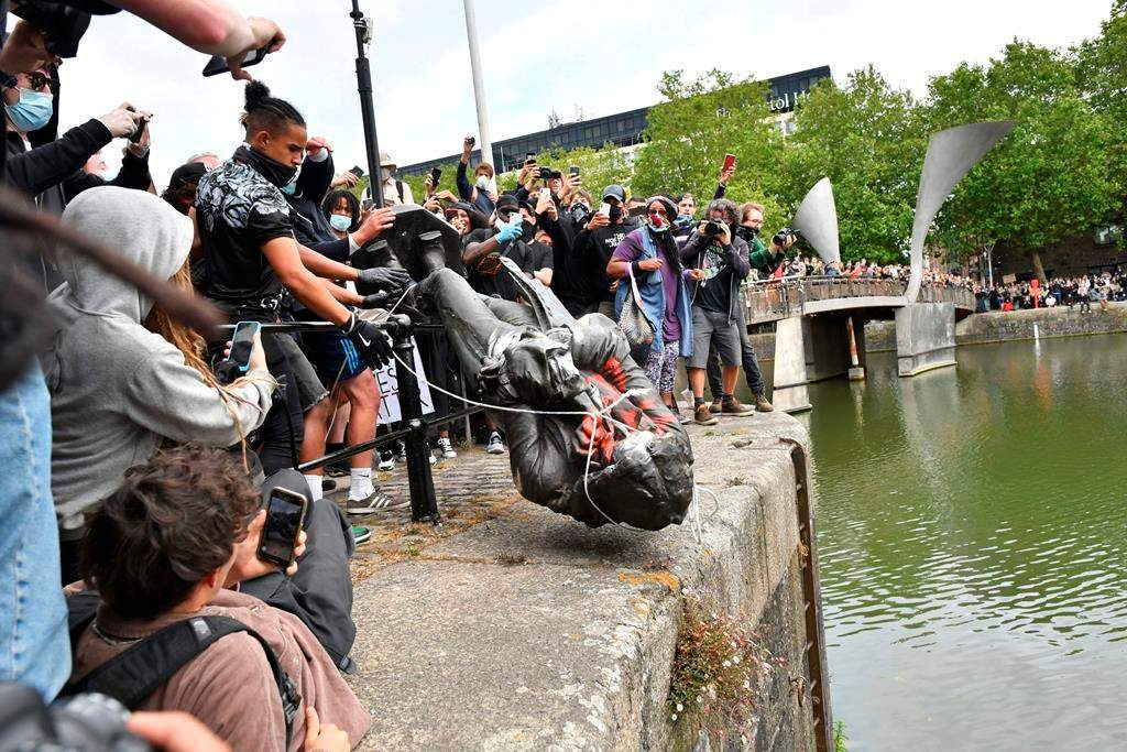 Protesters throw a statue of slave trader Edward Colston into Bristol Harbour during a Black Lives Matter protest rally in Bristol, England, Sunday, June 7, 2020, in response to the recent killing of George Floyd by police officers in Minneapolis, which has led to protests in many countries and across the U.S. (Ben Birchall/PA via AP)