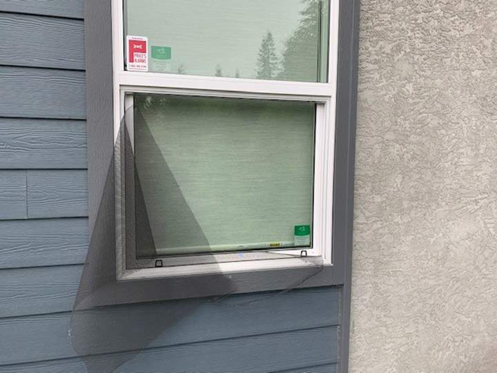 A window screen showing alleged damage from a knife.