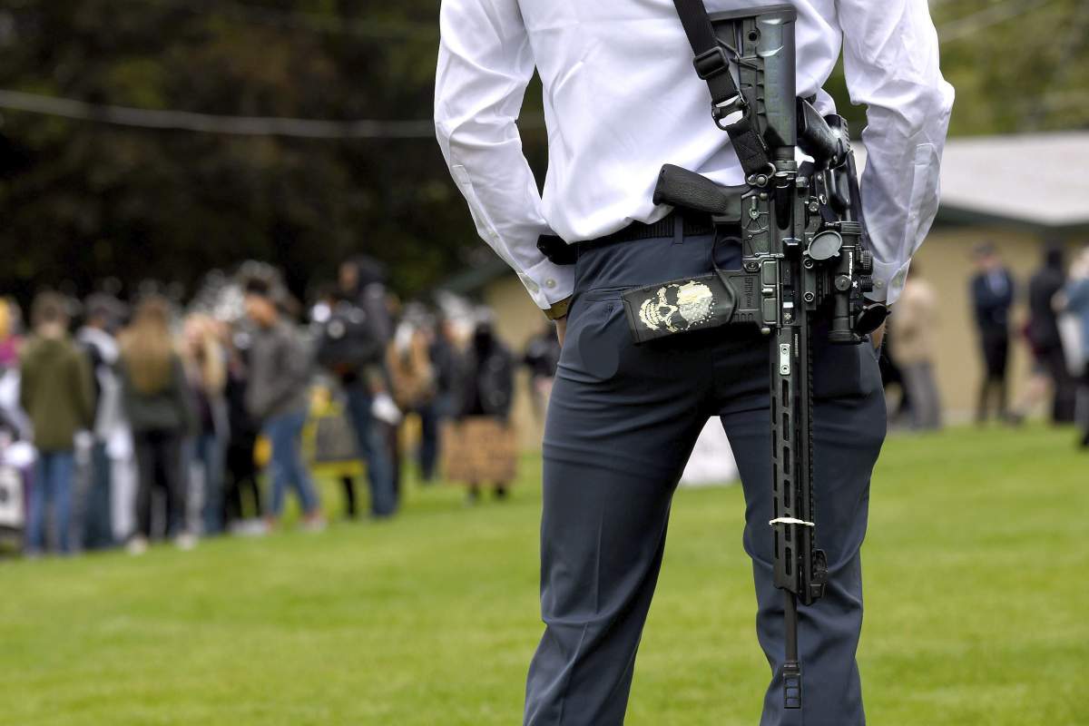 Armed citizen Kyle Rutherford, of Coeur d’Alene, Idaho, watches over a memorial service at Person Field in Coeur d’Alene, Sunday, June 7, 2020.