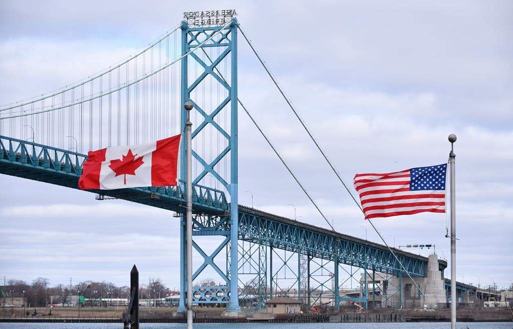 Canadian and American flags fly near the Ambassador Bridge at the Canada-USA border crossing in Windsor, Ont. on Saturday, March 21, 2020. THE CANADIAN PRESS/Rob Gurdebeke.