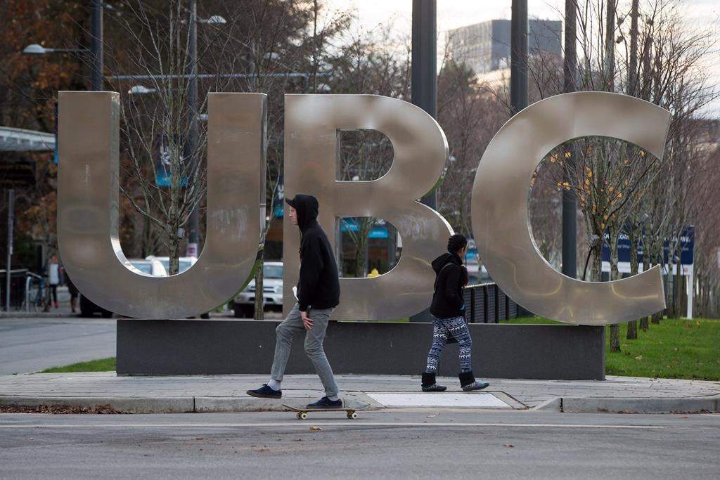 A man on a skateboard and a young woman pass large letters spelling out UBC at the University of British Columbia in Vancouver, B.C., Sunday, Nov. 22, 2015. THE CANADIAN PRESS/Darryl Dyck.