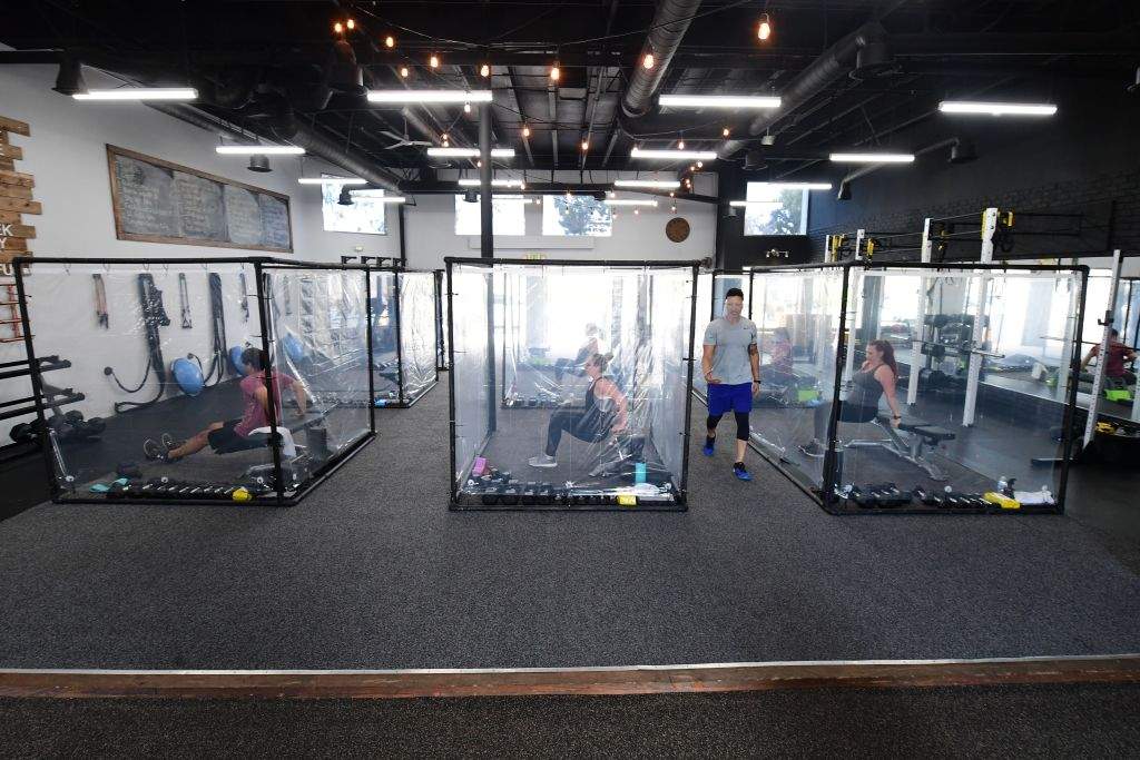 Peet Sapsin leads a class at Inspire South Bay Fitness with students behind plastic sheets in their workout pods while observing social distancing on June 15, 2020 in Redondo Beach, California, as the gym reopens today under California’s coronavirus Phase 3 reopening guidelines.