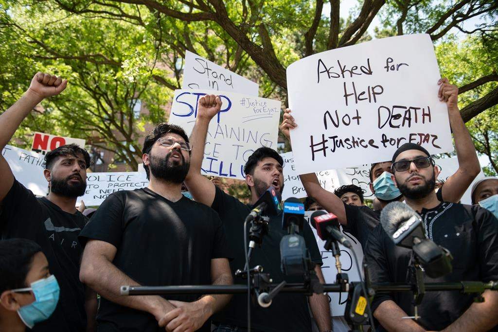Khizar Shahzad, left, Hashim Choudhary, second from left, and Hassan Choudhary, centre, shout for justice at the end of a press conference in front of the apartment building where their uncle, Ejaz Choudry, 62.
