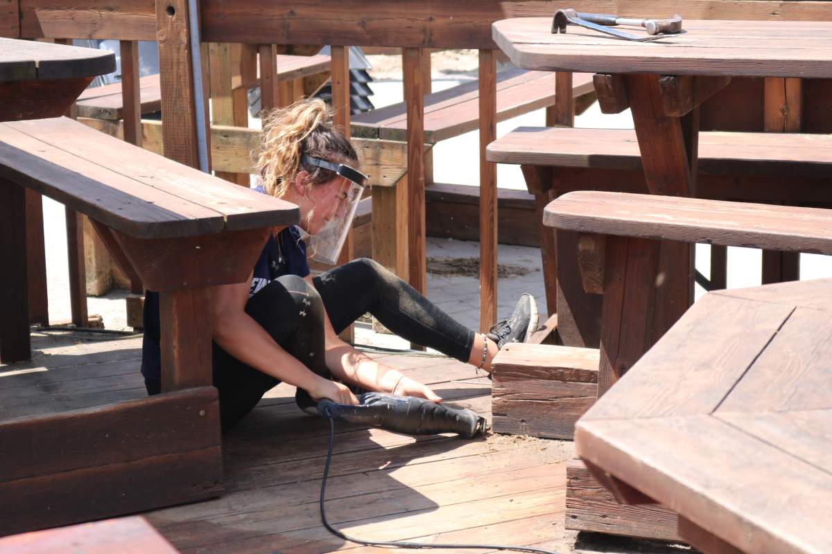 Ally Carr, an employee at GT’s On The Beach in Port Stanley is helping the restaurant get ready to open for Phase 2 by moving tables on the patio to ensure physical distancing. June 11, 2020.