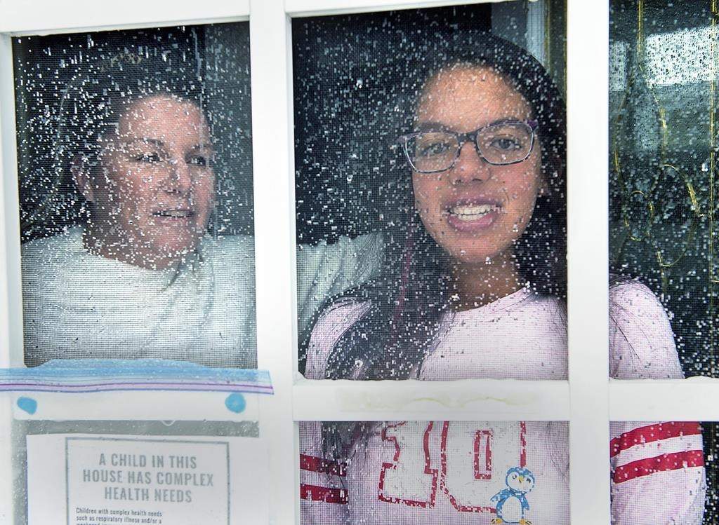 Lisa Ali and her 15-year-old daughter Tahlia look out from the front door of their Halifax-area home in Cole Harbour, N.S., on March 24, 2020.