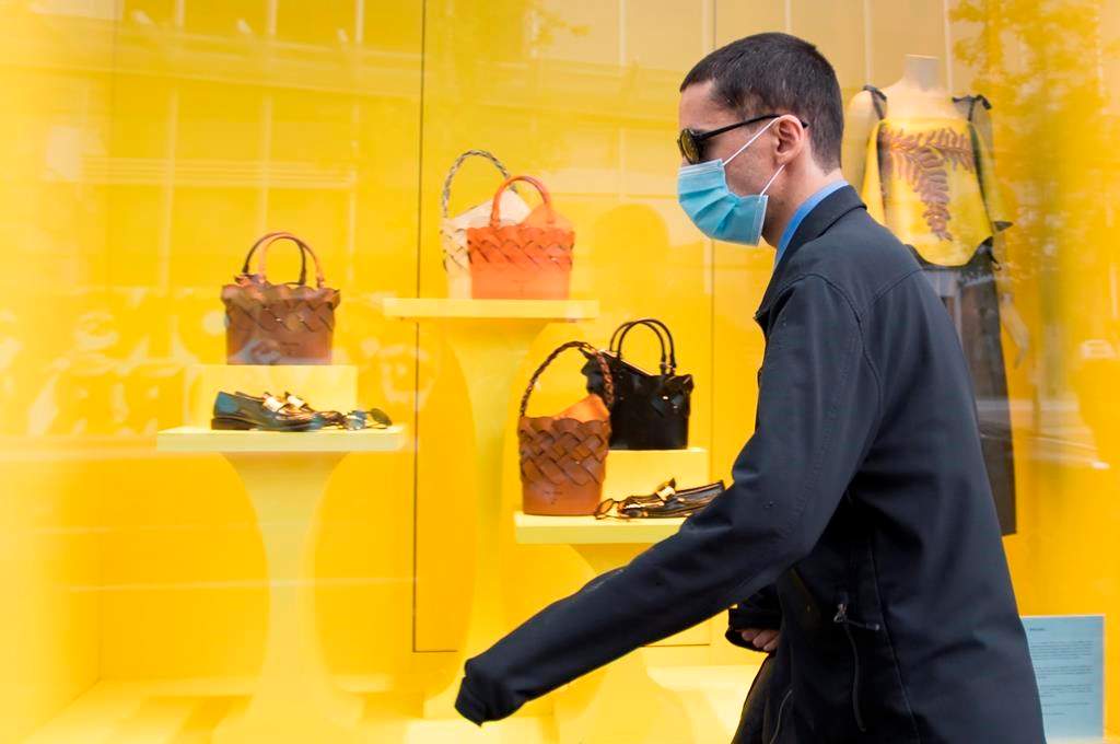 A pedestrian wears a protective face mask as they walk past a re-opened shop in downtown Vancouver, Tuesday, June 2, 2020.