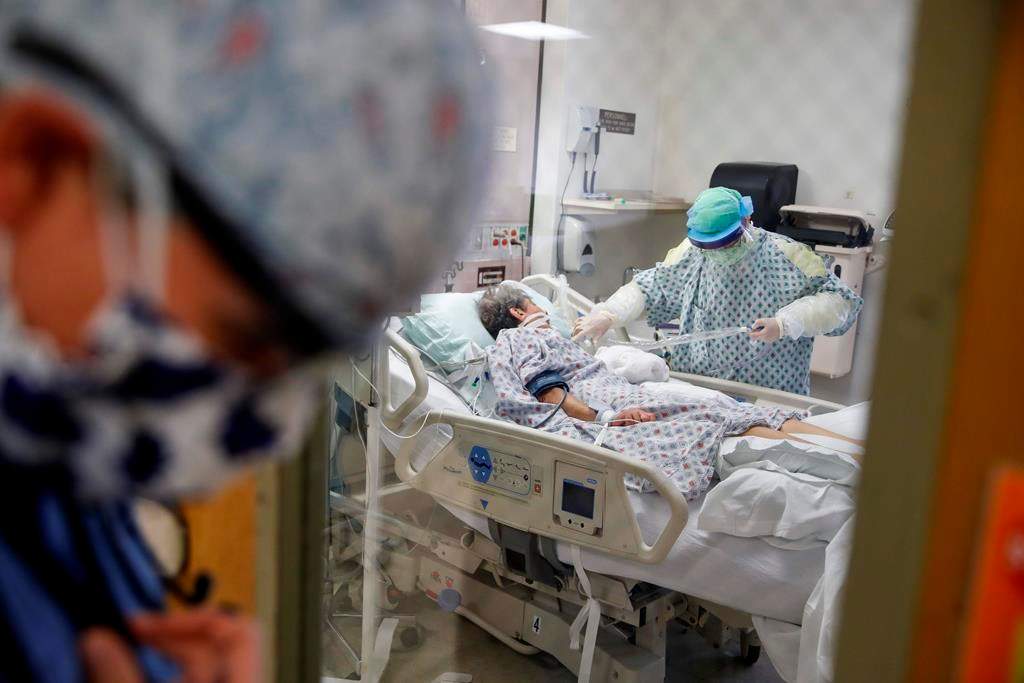 In this file photo, a resident physician stands outside a room at an Intensive Care Unit as a nurse suctions the lungs of a COVID-19 patient at St. Joseph’s Hospital, N.Y.