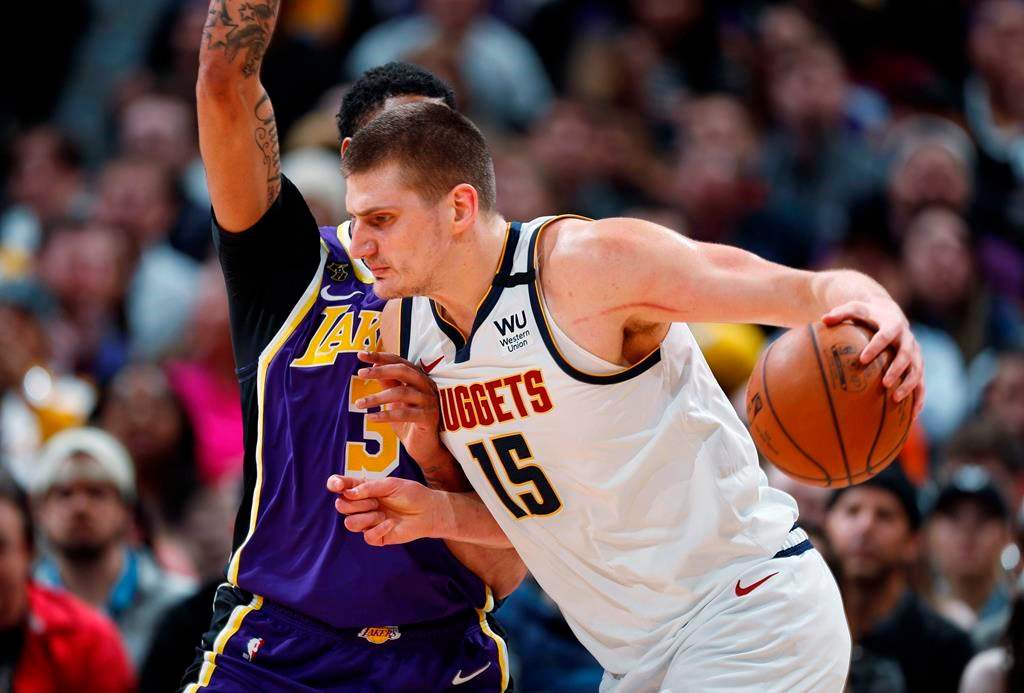 FILE - In this Feb. 12, 2020, file photo, Denver Nuggets center Nikola Jokic drives as Los Angeles Lakers forward Anthony Davis defends during the first half of an NBA basketball game in Denver. A person with knowledge of the situation says Jokic has tested positive for the coronavirus and is quarantining in his native Serbia. (AP Photo/David Zalubowski, File).