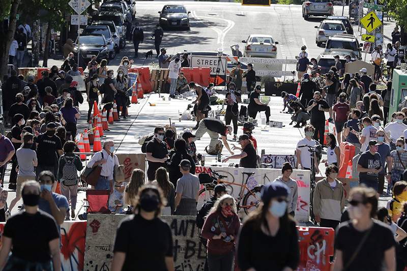 In this June 11, 2020 photo, artists paint large letters that read “Black Lives Matter” on a street near Cal Anderson Park inside what is being called the "Capitol Hill Autonomous Zone" in Seattle.