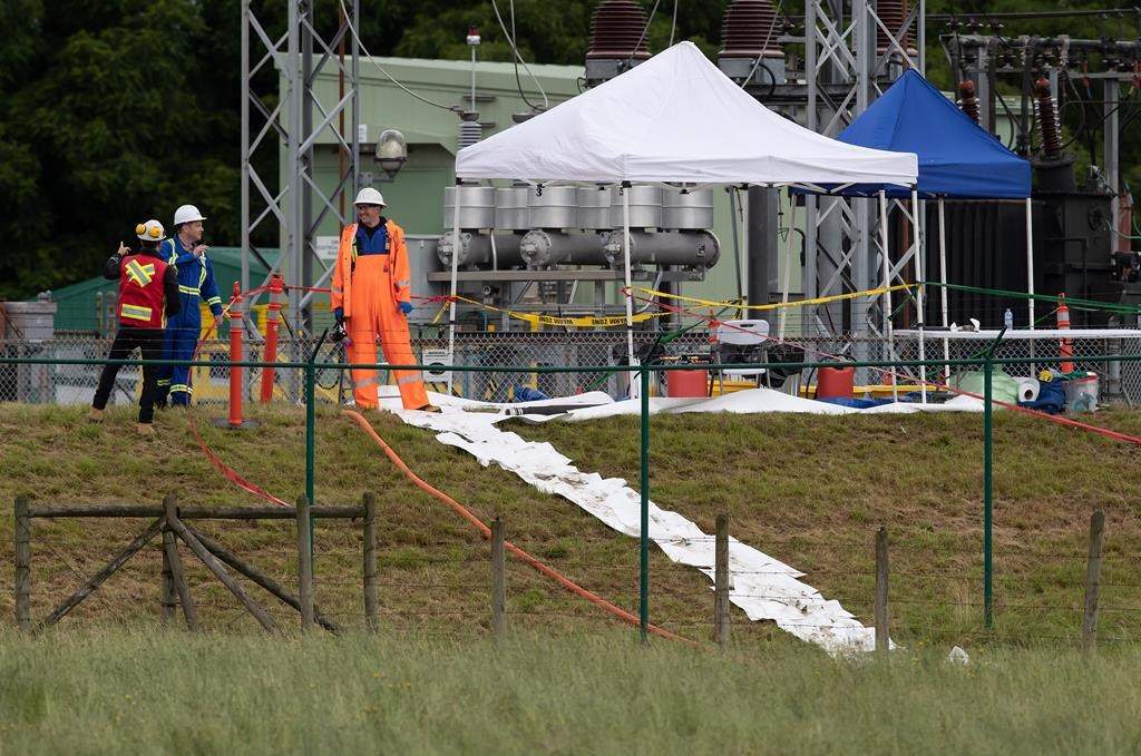 Workers are seen at the site of a crude oil spill at a Trans Mountain Pipeline pump station in Abbotsford, on Sunday, June 14, 2020.