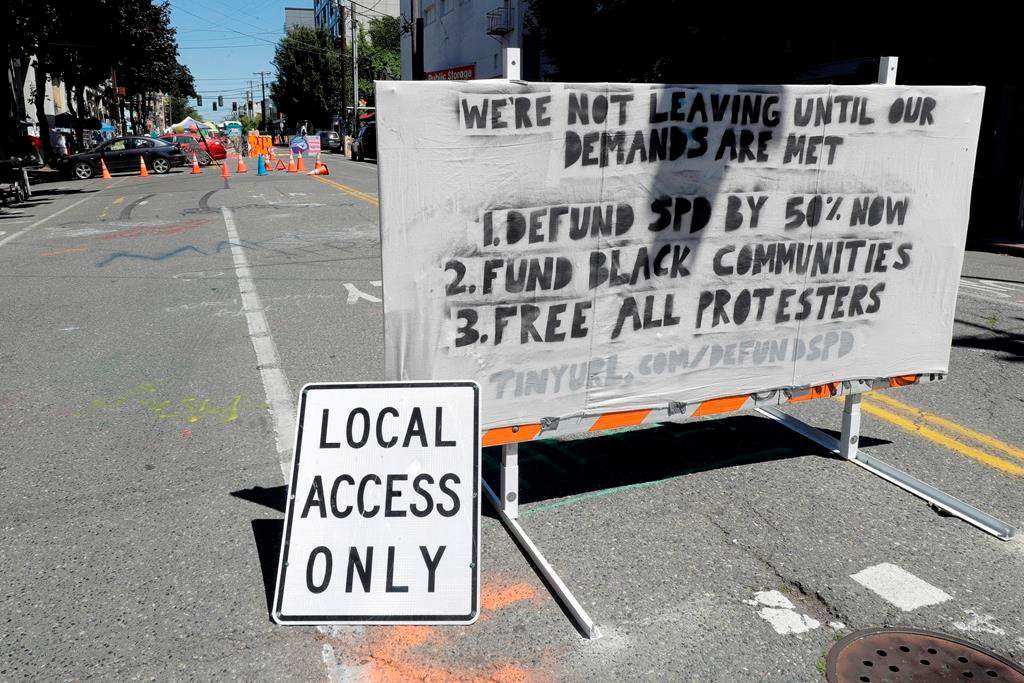 A sign on a street barricade lists some of the demands of protesters in what has been named the Capitol Hill Occupied Protest zone in Seattle, Monday, June 22, 2020. For the second time in less than 48 hours, there was a shooting near the \”CHOP\” area that has been occupied by protesters after Seattle Police pulled back from several blocks of the city\’s Capitol Hill neighborhood near the Police Department\’s East Precinct building.