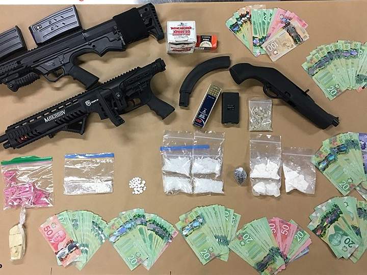 A police photo showing money, drugs and firearms that were allegedly seized during two simultaneous drug busts in West Kelowna on Tuesday.