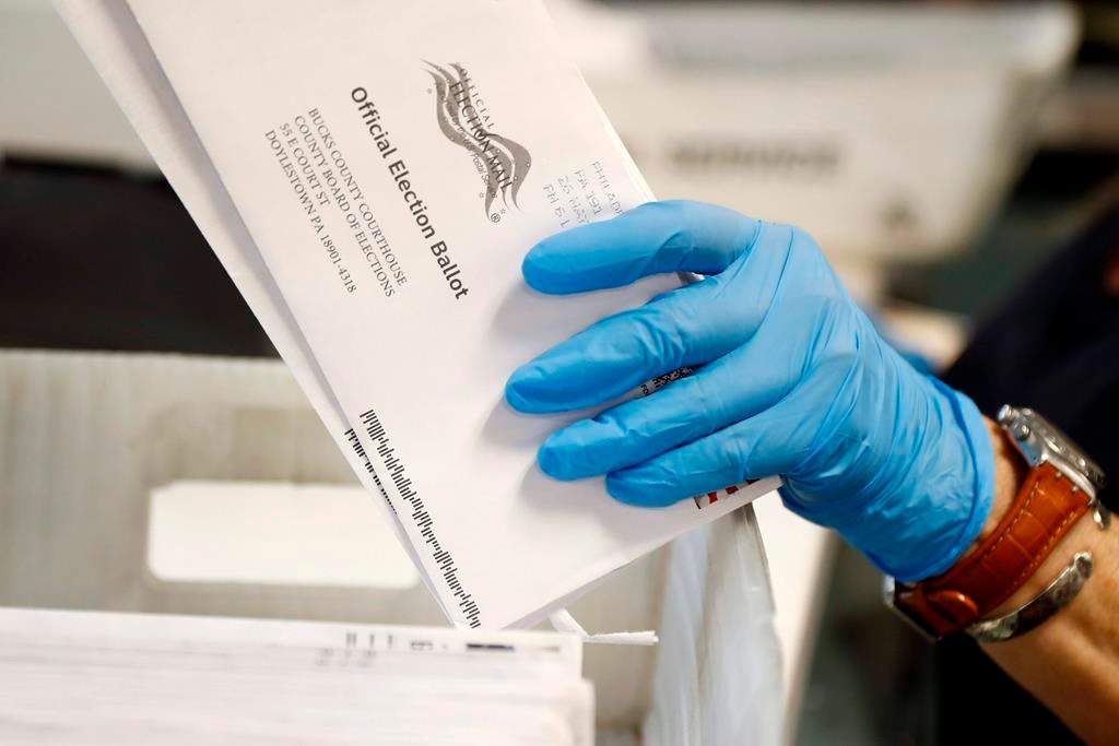FILE - In this May 27, 2020 file photo, a worker processes mail-in ballots at the Bucks County Board of Elections office prior to the primary election in Doylestown, Pa. A network of deep-pocketed progressive donors are launching a $59 million effort to encourage people of color to vote by mail in November, a step many Democrats view as crucial to turning out the party's base during a global pandemic. (AP Photo/Matt Slocum, File).