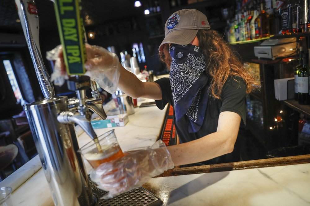 In this June 22, 2020, file photo, a bartender pours a beer for a customer at Shade Bar NYC in New York.