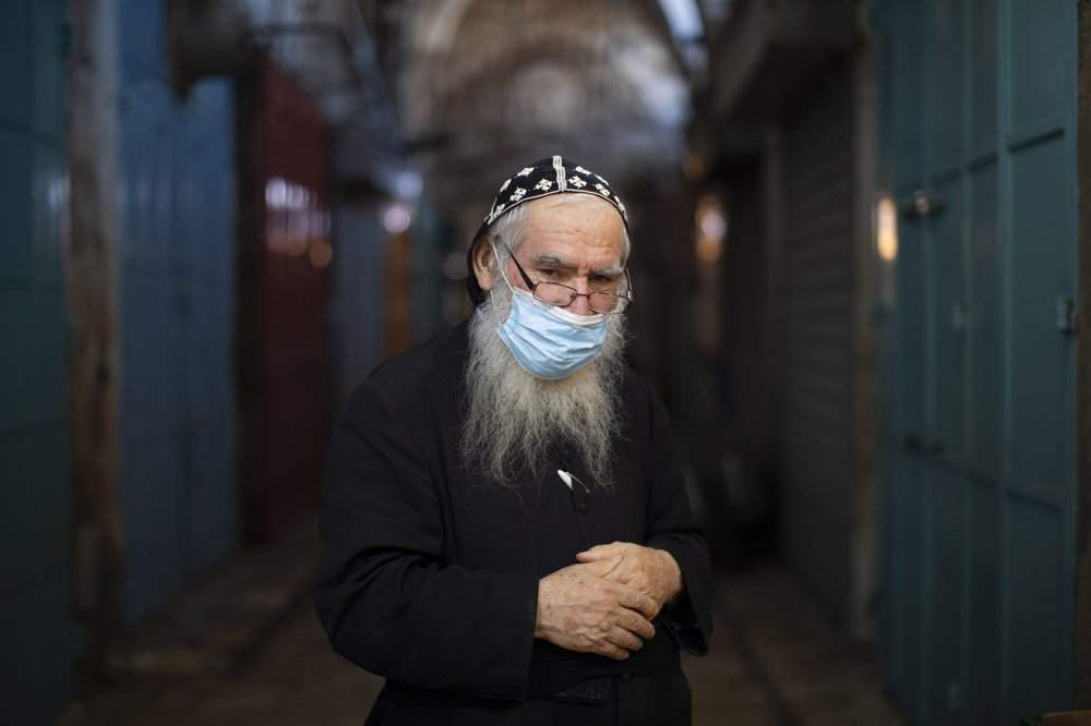 Syrian Orthodox priest, Shimon Jan, 70, poses for a portrait wearing his protective face mask in the alleys of Jerusalem’s Old City, Tuesday, July 21, 2020.