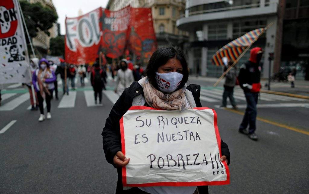 FILE PHOTO: A demonstrator holds a placard that reads "their richness is our poverty", during a protest to demand resources for the vulnerable, amid the coronavirus disease (COVID-19) lockdown, in Buenos Aires, Argentina May 21, 2020. 