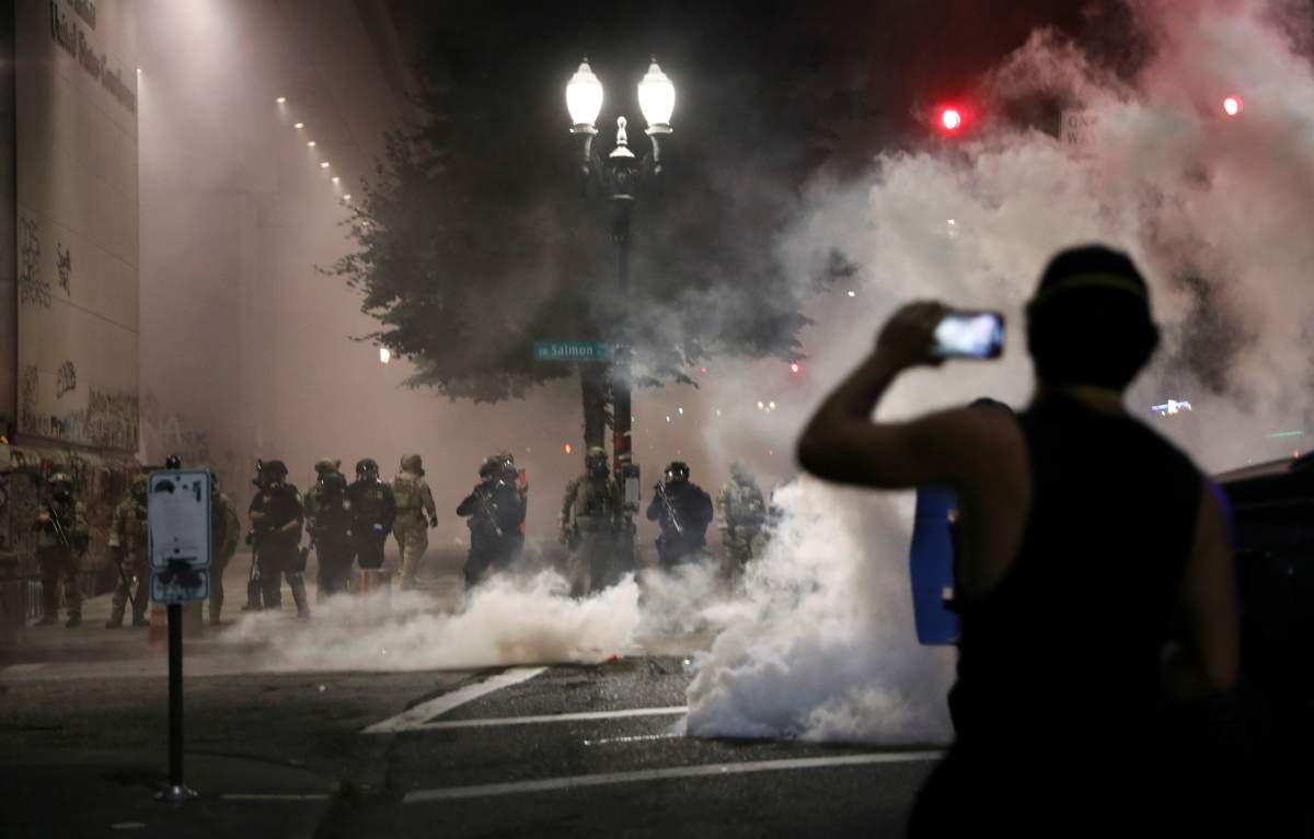 A demonstrator holds a mobile phone in front of federal law enforcement officials during a protest against racial inequality in Portland, Ore., July 21, 2020.