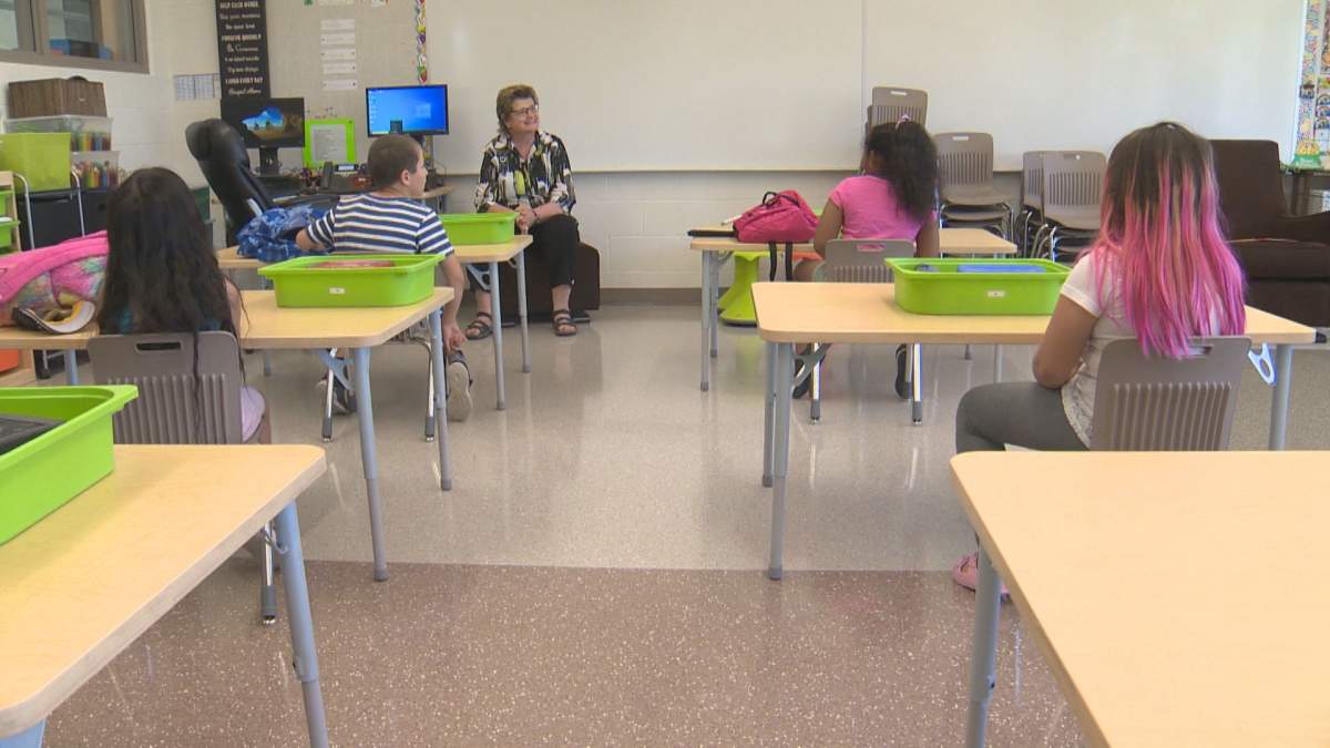 Students sit in a physically-distanced classroom for small group sessions with their teacher to end the school year in June. 