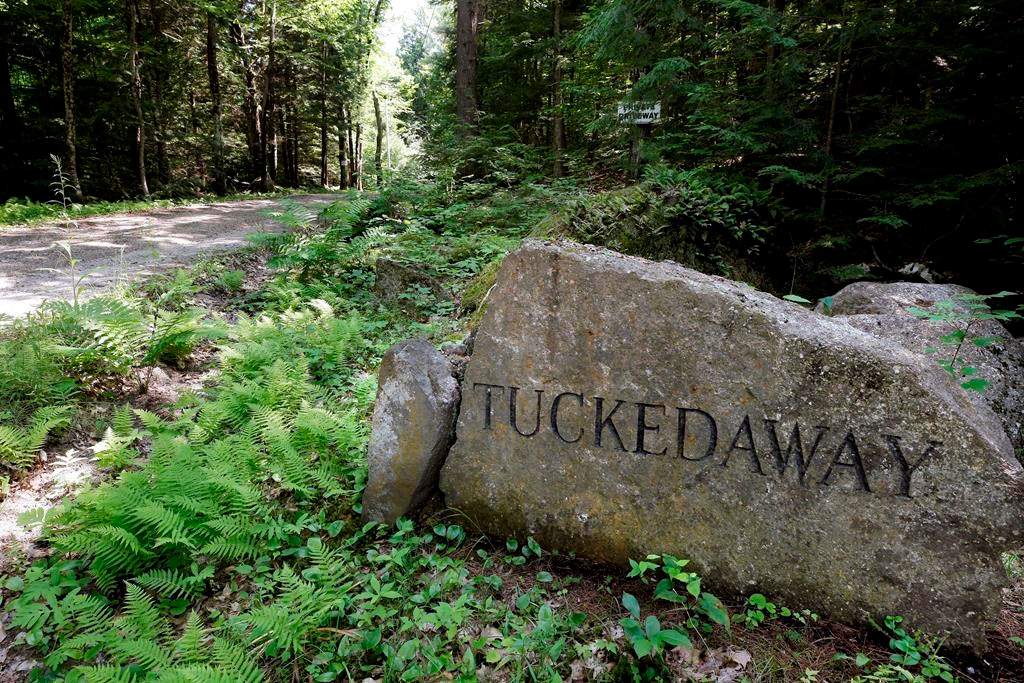 A boulder inscribed with “Tucked Away” sits beside a road going to an estate where Ghislaine Maxwell was taken into custody, Thursday, July 2, 2020, in Bradford, N.H. The British socialite faces charges she helped recruit three girls — one as young as 14 — to have sex with financier Jeffrey Epstein, who was accused of sexually assaulting dozens of girls and women over many years. (AP Photo/Steven Senne)
