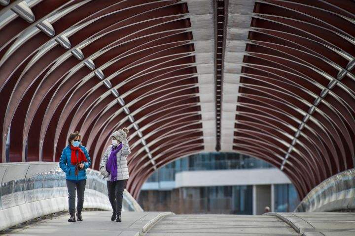 Two women wear masks as people practice physical distancing in Calgary, Alta., Thursday, April 9, 2020, amid a worldwide COVID-19 pandemic. 