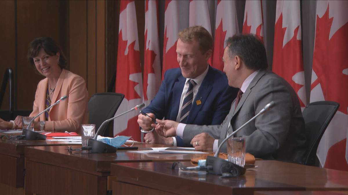 Indigenous services minister Marc Miller (middle) and Assembly of First Nations national Chief Perry Bellegarde sign an agreement to advance the transfer of child welfare services to Indigenous communities.