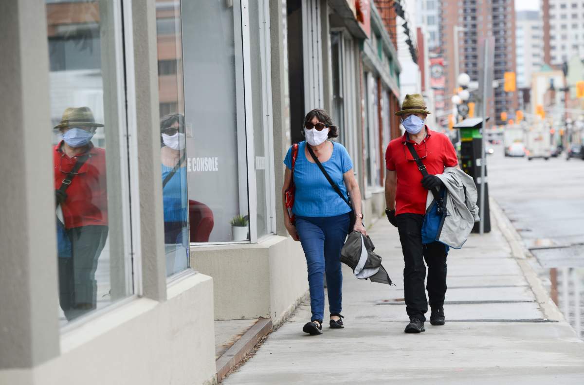 A couple wear masks while out for a walk in downtown Ottawa during the COVID-19 pandemic on Friday, May 1, 2020.
