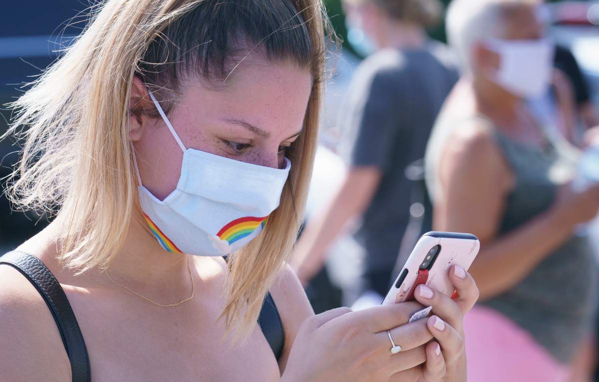 A woman checks her phone as she waits in line to enter a mobile COVID-19 test clinic in Mercier, Que., on Thursday.