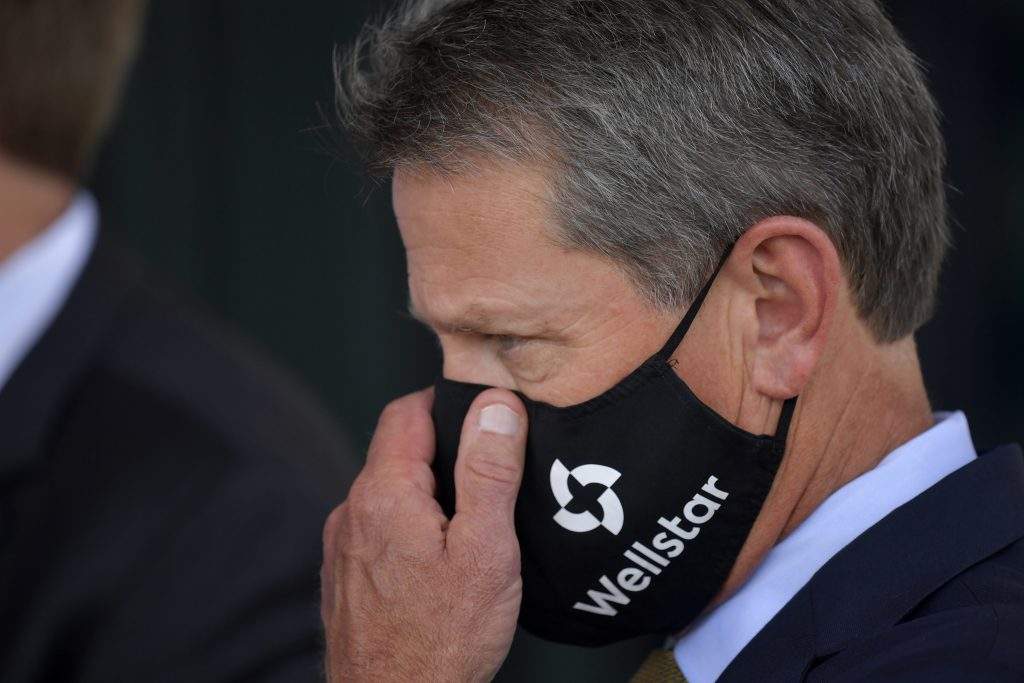 Georgia Gov. Brian Kemp adjusts his mask prior to a bill signing at Wellstar Kennestone Hospital where the hospital opened a new Emergency Room space, Thursday, July 16, 2020, in Marietta, Ga. Mayors in Atlanta and other Georgia cities deepened their defiance of Gov. Kemp on Thursday, saying they want their requirements for people to wear masks in public to remain in place, even after the Republican governor explicitly forbade cities and counties from mandating face coverings.