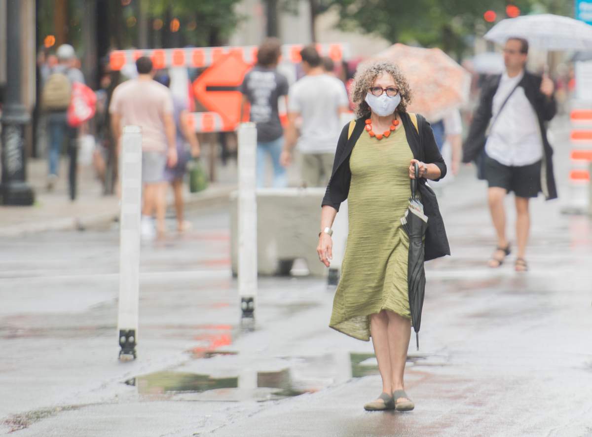 A woman wears a face mask as she walks along a street in Montreal, Saturday, July 11, 2020, as the COVID-19 pandemic continues in Canada and around the world.  