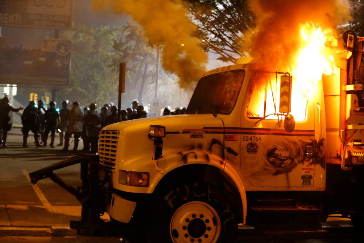 Police stand in front of a utility vehicle that was set on fire by protesters during a demonstration outside the Richmond Police Department headquarters on Grace Street in Richmond, Va., July 25, 2020.