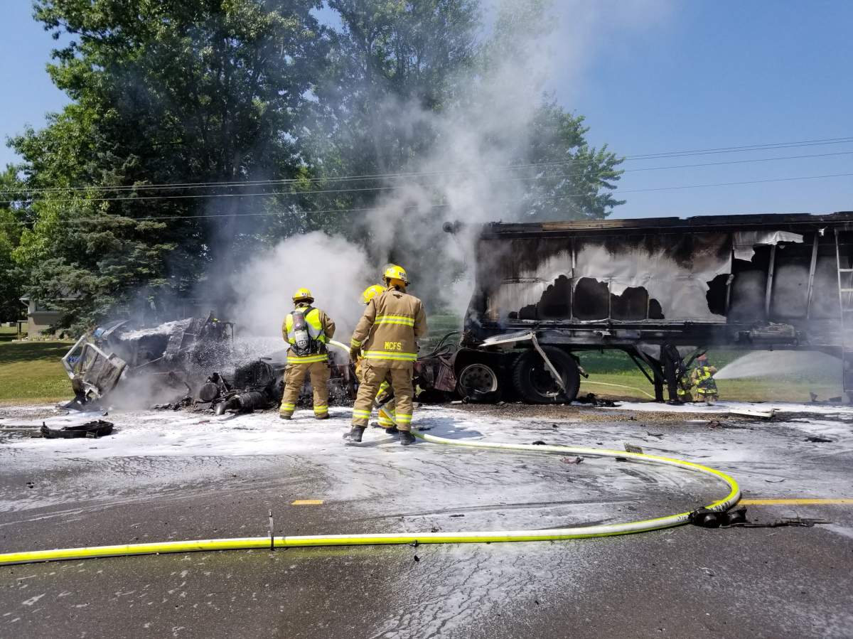 Firefighters are seen dousing flames after two vehicles collided on Highbury Ave. N.