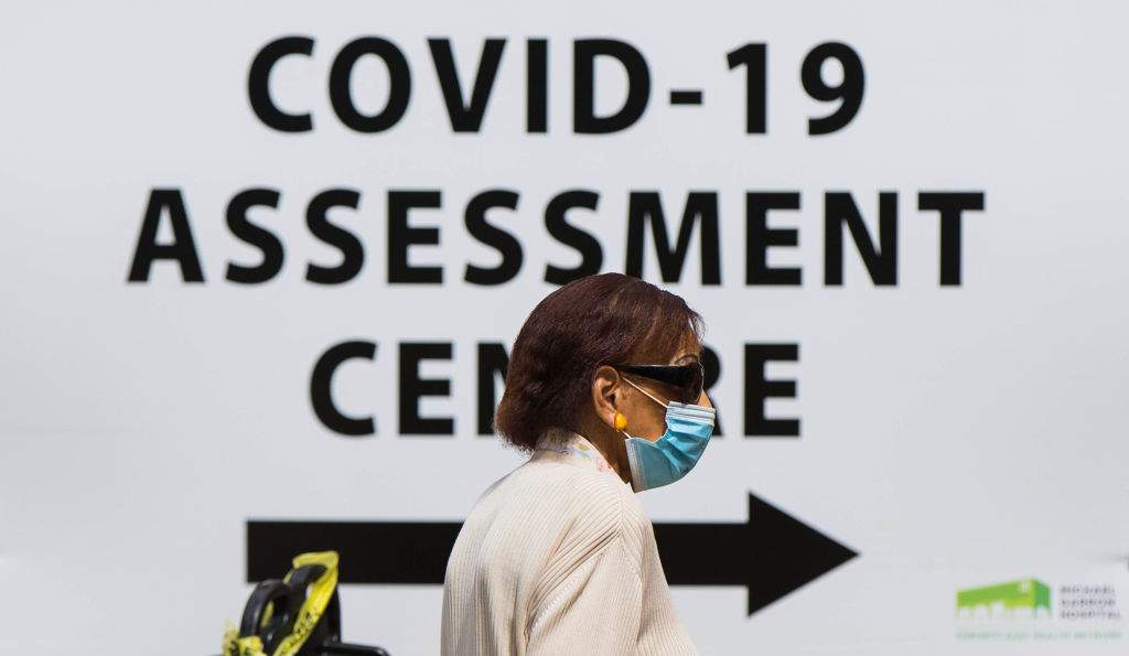 FILE - A woman wearing a face mask arrives at the COVID-19 assessment center of a hospital in Toronto, Canada, July 20, 2020.