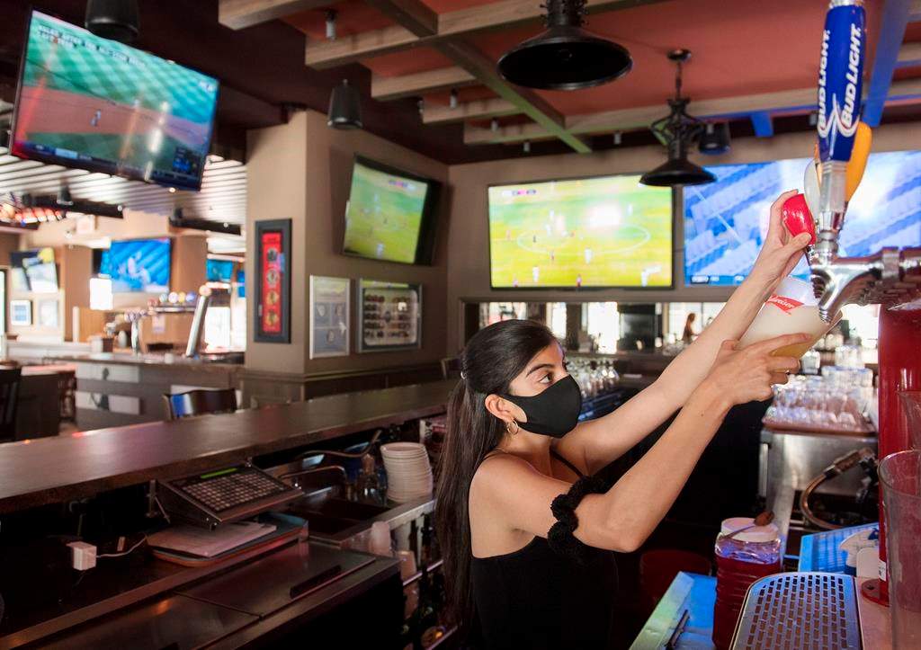A server pulls a pint of beer at Station Sports bar in Montreal, Saturday, July 25, 2020, as the COVID-19 pandemic continues in Canada and around the world. THE CANADIAN PRESS/Graham Hughes.